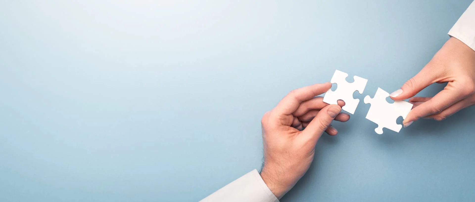 Two hands connecting puzzle pieces